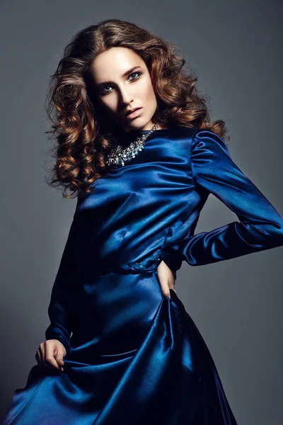 Alta moda look.glamour ritratto di bella sexy elegante bruna caucasica giovane donna modello con trucco luminoso, con capelli ricci sani in abito blu brillante in studio — Foto Stock