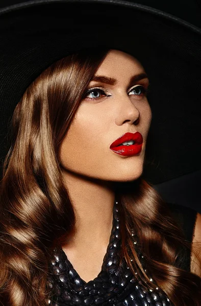 High fashion look.glamor close seup portrait of beautiful sexy stylish Caucasian young woman model with bright makeup, with red lips, with perfect clean skin in big black hat — стоковое фото