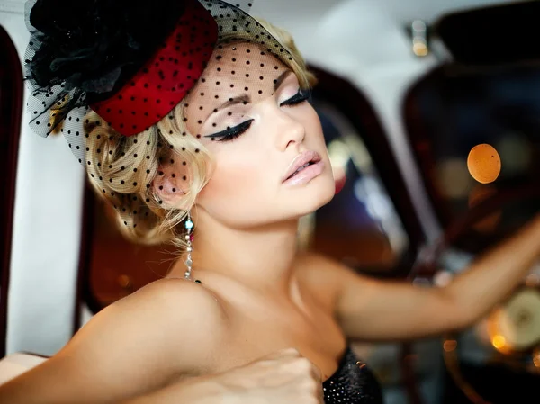 Retrato de hermosa moda sexy modelo de chica rubia elegante con maquillaje brillante en estilo retro sentado en el coche viejo —  Fotos de Stock