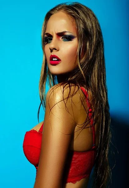 High fashion look.glamor close seup portrait of beautiful sexy stylish Caucasian young woman model with bright makeup, with red lips, with perfect clean skin in red lingerie on blue background — стоковое фото