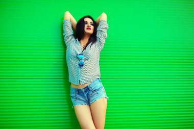 portre sevimli komik seksi genç şık gülümseyen kadın kız modeli kot şort parlak modern kumaş pembe dudakları mükemmel sunbathed vücut açık havada kenti yakınlarındaki yeşil duvar ile