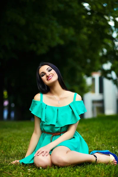 Портрет милої смішної сексуальної молодої стильної усміхненої жінки-моделі дівчини в яскравій сучасній зеленій сукні з ідеальним засмаганим тілом на відкритому повітрі в парку — стокове фото