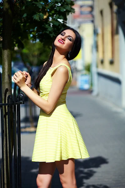 Portrait of cute funny sexy young stylish smiling woman girl model in bright modern yellow dress with perfect sunbathed body outdoors in the park — Stock Photo, Image