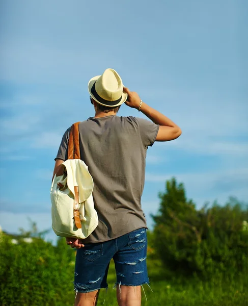 背面有吸引力现代时尚的年轻人在休闲布在帽子在眼镜的背后蓝蓝的天空 — 图库照片