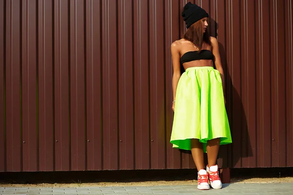 Portrait of sexy teenager urban modern young stylish woman girl  model in bright modern cloth in green colotful skirt outdoors in the street standing near wall — Stock Photo, Image