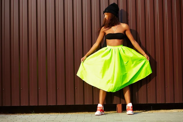 Portrait of sexy teenager urban modern young stylish woman girl  model in bright modern cloth in green colotful skirt outdoors in the street standing near wall — Stock Photo, Image