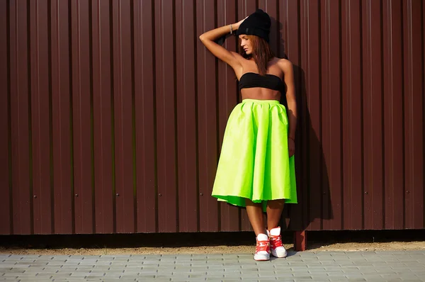 Portrait of sexy teenager urban modern young stylish woman girl  model in bright modern cloth in green colotful skirt outdoors in the street standing near wall — Stock Photo, Image