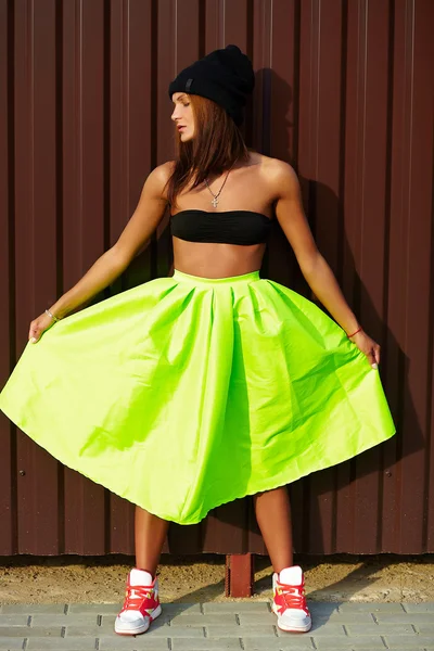 Portrait of sexy teenager urban modern young stylish woman girl  model in bright modern cloth in green colotful skirt outdoors in the street standing near wall — Stock Photo, Image