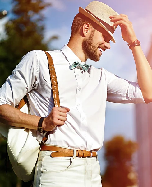 Νεαρός χαμογελαστό κομψό σέξι μοντέλο όμορφος άνθρωπος τουριστικά στον τρόπο ζωής των casual ύφασμα στο δρόμο με το καπέλο με τσάντα — Φωτογραφία Αρχείου