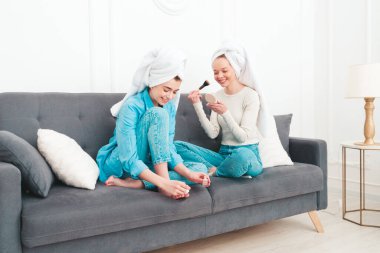 İki güzel, güzel, gülümseyen kadın lüks bir dairede ya da otel odasında poz veren kaygısız mankenler. Makyaj yapıyor, kafalarına havlu takıyor ve tırnaklarını ojeyle boyuyorlar.