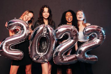 Yeni yılı kutlayan güzel kadınlar. Yeni yıl partisinde eğlenen, şık, seksi parti elbiseli, elinde balon tutan güzel kadınlar. Tatil kutlamaları. Büyüleyici mankenler. 