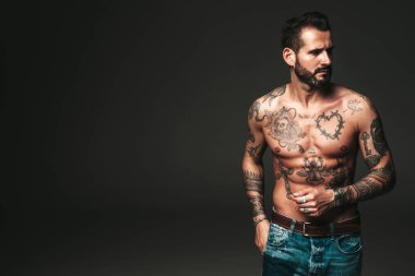 Yakışıklı, kendine güvenen, stil sahibi hipster Lambersex modelinin portresi. Seksi, modern adam. Dövmeli çıplak gövde. Stüdyoda siyah arka planda poz veren moda erkek.