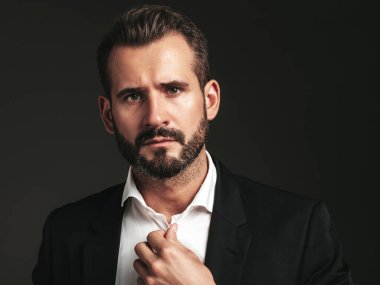 Yakışıklı, kendine güvenen, stil sahibi hipster Lambersex modelinin portresi. Zarif siyah takım elbiseli seksi modern adam. Moda erkeği karanlık arka planda stüdyoda poz veriyor. Kameraya bakıyorum. 
