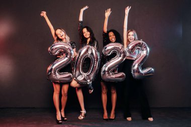 Yeni yılı kutlayan güzel kadınlar. Yeni yıl partisinde eğlenen, şık, seksi parti elbiseli, elinde balon tutan güzel kadınlar. Tatil kutlamaları. Büyüleyici mankenler. 