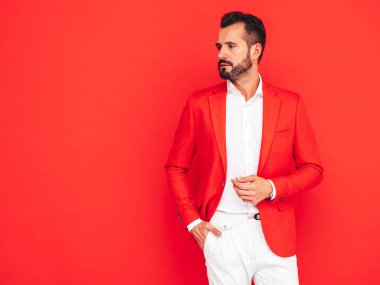 Yakışıklı, kendine güvenen, stil sahibi hipster Lambersex modelinin portresi. Zarif takım elbiseli seksi modern adam. Moda erkeği kırmızı duvarın yanındaki stüdyoda poz veriyor.