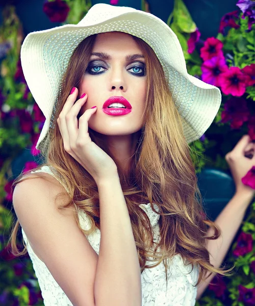 High fashion look.glamor close seup portrait of beautiful sexy stylish blond young woman model with bright makeup and pink lips with perfect clean skin in hat near summer flowers — стоковое фото