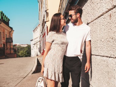 Gülümseyen güzel kadın ve yakışıklı erkek arkadaşı. Gündelik yaz kıyafetleri giymiş bir kadın. Mutlu, neşeli bir aile. Kadın eğleniyor. Güneş gözlükleriyle sokakta poz veren çift. Birbirlerine sarılıyorlar.