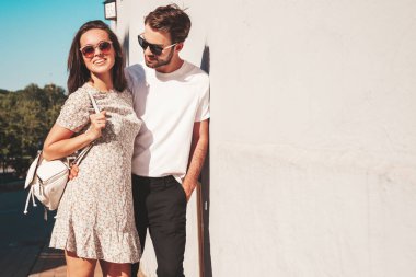 Gülümseyen güzel kadın ve yakışıklı erkek arkadaşı. Gündelik yaz kıyafetleri giymiş bir kadın. Mutlu, neşeli bir aile. Kadın eğleniyor. Güneş gözlükleriyle sokakta poz veren çift. Birbirlerine sarılıyorlar.