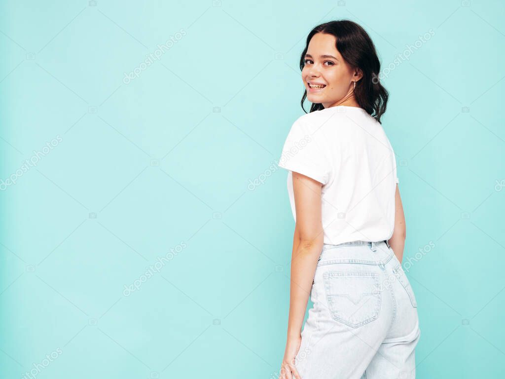 Portrait of young beautiful smiling female in trendy summer clothes. Sexy carefree woman posing near blue wall in studio. Positive model having fun indoors. Cheerful and happy