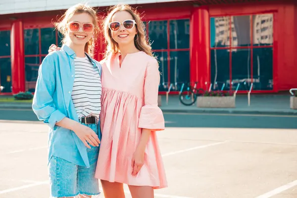 Son moda yaz kıyafetleri içinde iki güzel, gülümseyen hippi kadın. Sokakta poz veren kaygısız kadınlar. Pozitif saf modeller gün batımında eğleniyorlar, sarılıyorlar. 