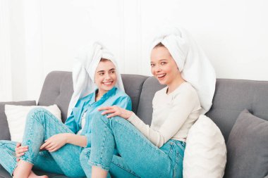 Kanepede oturan iki güzel, gülümseyen kadın. Havalı bir dairede ya da otel odasında poz veren kaygısız seksi modeller. Evde kafalarına havlu geçirip güzellik tedavisi yapıyorlar.