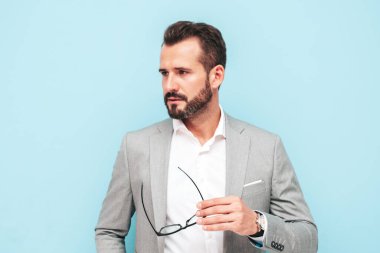 Yakışıklı, kendine güvenen, stil sahibi, Lambersexual modelin yakın portresi. Zarif takım elbiseli, modern bir adam. Moda erkeği stüdyoda mavi duvarın yanında poz veriyor.