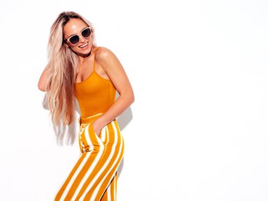 Son moda sarı elbiseli, gülümseyen, güzel sarışın kadın. Stüdyoda beyaz tenli, kaygısız seksi kadın. Pozitif model içeride eğleniyor. Neşeli ve mutlu. Güneş gözlükleriyle