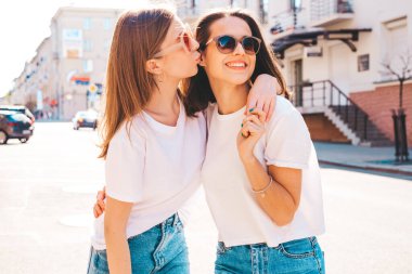 Moda kıyafetleri içinde iki güzel, gülümseyen yeniyetme kadın portresi. Sokakta poz veren kaygısız kadınlar. Pozitif modeller eğleniyor, sarılıyor ve deliriyor.