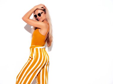 Son moda sarı elbiseli, gülümseyen, güzel sarışın kadın. Stüdyoda beyaz tenli, kaygısız seksi kadın. Pozitif model içeride eğleniyor. Neşeli ve mutlu. Güneş gözlükleriyle