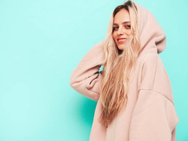 Son moda yaz kapüşonlu güzel, gülümseyen bir kadın. Stüdyoda mavi duvarın yanında poz veren kaygısız seksi kadın. Pozitif sarışın model eğleniyor ve deliriyor. Neşeli ve mutlu