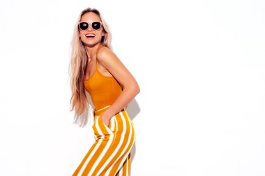 Son moda sarı elbiseli, gülümseyen, güzel sarışın kadın. Stüdyoda beyaz tenli, kaygısız seksi kadın. Pozitif model içeride eğleniyor. Neşeli ve mutlu. Güneş gözlükleriyle