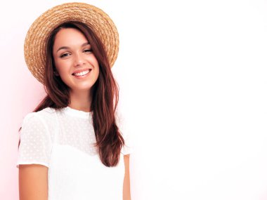 Moda kıyafetleri içinde gülümseyen güzel bir kadın. Stüdyoda pembe duvarın yanında poz veren kaygısız seksi kadın. Pozitif esmer model eğleniyor. Neşeli ve mutlu. Şapkalı.