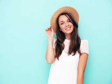 Moda kıyafetleri içinde gülümseyen güzel bir kadın. Stüdyoda mavi duvarın yanında poz veren kaygısız seksi kadın. Pozitif esmer model eğleniyor. Neşeli ve mutlu. Şapkalı.