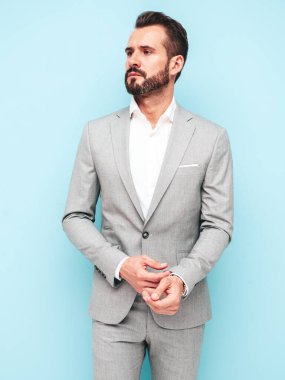 Yakışıklı, kendine güvenen, stil sahibi, Lambersex modelinin portresi. Zarif takım elbise giymiş modern bir adam. Moda erkeği stüdyoda mavi duvarın yanında poz veriyor. 