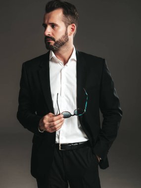 Yakışıklı, kendine güvenen, stil sahibi hipster Lambersex modelinin portresi. Zarif siyah takım elbiseli seksi modern adam. Moda erkeği karanlık arka planda stüdyoda poz veriyor. Kameraya bakıyorum. 