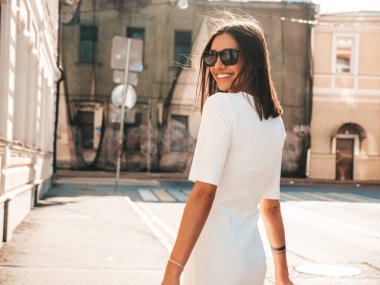 Yeni moda beyaz elbiseli, güzel, gülümseyen, hippi bir kadın. Günbatımında sokakta poz veren kaygısız seksi kadın. Açık havada pozitif model. Neşeli ve mutlu 