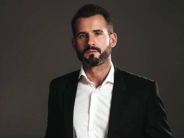 Yakışıklı, kendine güvenen, stil sahibi hipster Lambersex modelinin portresi. Zarif siyah takım elbiseli seksi modern adam. Moda erkeği karanlık arka planda stüdyoda poz veriyor. Kameraya bakıyorum. 