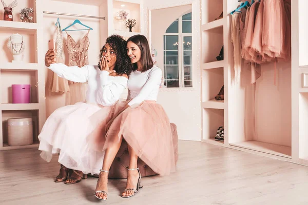 Son moda yaz elbiseleri içinde gülümseyen iki güzel uluslararası hippi kadın. Pembe gardıropta poz veren kaygısız seksi kadınlar. Pozitif modeller eğleniyor. Arkadaşlık kavramı. Selfie çekiyorlar.