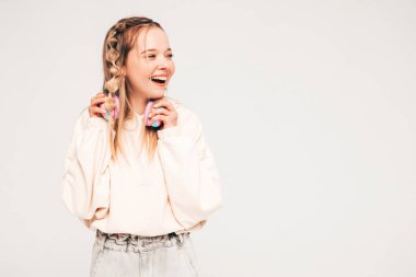 Yazlık kıyafetler giymiş güzel, gülen bir kadın. Kablosuz kulaklıkla müzik dinleyen seksi tasasız model. Stüdyoda güneş gözlükleriyle gri arka planda poz veren sevimli ve pozitif kadın.