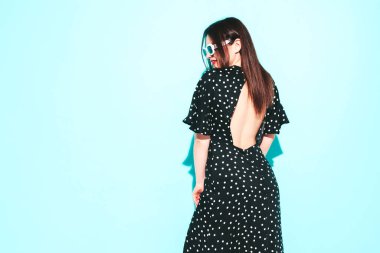 Stüdyoda mavi duvarın yanında poz veren şık, esmer bir kadının moda portresi. Kırmızı dudaklı, modaya uygun bir kadın. 