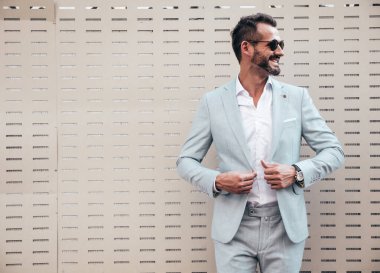 Yakışıklı, kendine güvenen, havalı, Lambersex modelinin portresi. Zarif beyaz takım elbise giymiş modern bir adam. Moda erkeği gün batımında çitlerin yanında poz veriyor. Güneş gözlükleriyle