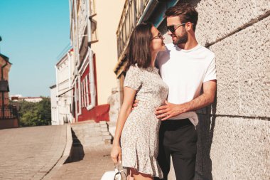 Gülümseyen güzel kadın ve yakışıklı erkek arkadaşı. Gündelik yaz kıyafetleri giymiş bir kadın. Mutlu, neşeli bir aile. Kadın eğleniyor. Güneş gözlükleriyle sokakta poz veren çift. Birbirlerine sarılıyorlar.