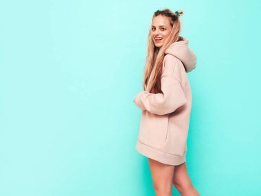 Son moda yaz kapüşonlu güzel, gülümseyen bir kadın. Stüdyoda mavi duvarın yanında poz veren kaygısız seksi kadın. Pozitif sarışın model eğleniyor ve deliriyor. Neşeli ve mutlu