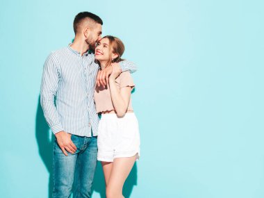 Seksi, gülümseyen güzel kadın ve yakışıklı erkek arkadaşı. Mutlu mutlu aile stüdyoda mavi duvarın yanında hassas anlar yaşıyor. Saf, neşeli modeller sarılıyor.