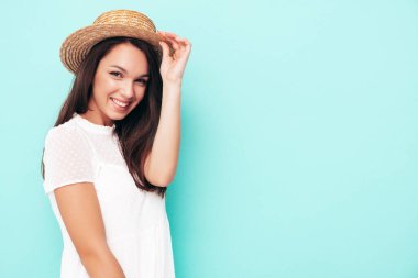 Moda kıyafetleri içinde gülümseyen güzel bir kadın. Stüdyoda mavi duvarın yanında poz veren kaygısız bir kadın. Pozitif esmer model eğleniyor. Neşeli ve mutlu. Şapkalı.