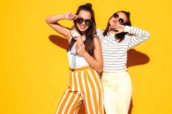 两个年轻美丽的金发嬉皮士女穿着时髦的夏装 无忧无虑的性感女人在工作室的黄墙边摆姿势 有乐趣的正面模型 快乐而快乐 戴太阳镜 — 图库照片