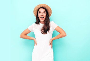 Moda kıyafetleri içinde gülümseyen güzel bir kadın. Stüdyoda mavi duvarın yanında poz veren kaygısız seksi kadın. Pozitif esmer model eğleniyor. Neşeli ve mutlu. Şapkalı.