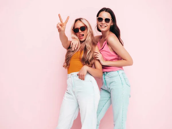 流行の夏服の2人の若い美しい笑顔ブルネットのヒップスター女性 ピンクの壁の近くにポーズをとる屈託のない女性 楽しい正のモデル 陽気で幸せ サングラスで — ストック写真