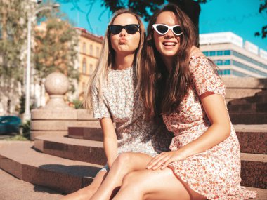 Son moda yaz elbiseleri içinde iki güzel, gülümseyen hippi kadın. Sokakta poz veren kaygısız kadınlar. Pozitif saf modeller gün batımında eğleniyor, sarılıyor ve deliriyor. Mutlu ve neşeli.
