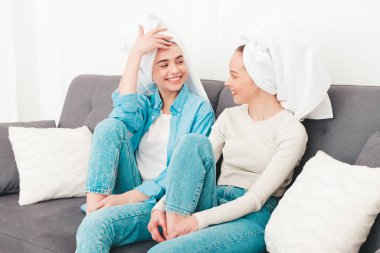 Kanepede oturan iki güzel, gülümseyen kadın. Havalı bir dairede ya da otel odasında poz veren kaygısız seksi modeller. Evde kafalarına havlu geçirip güzellik tedavisi yapıyorlar.